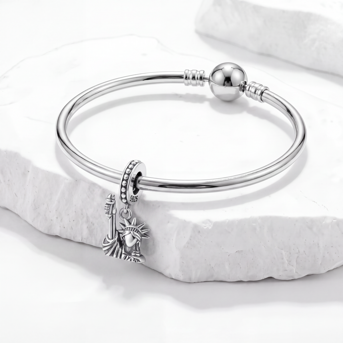 Travel charms bracelet featuring a miniature Statue of Liberty charm on a silver band.