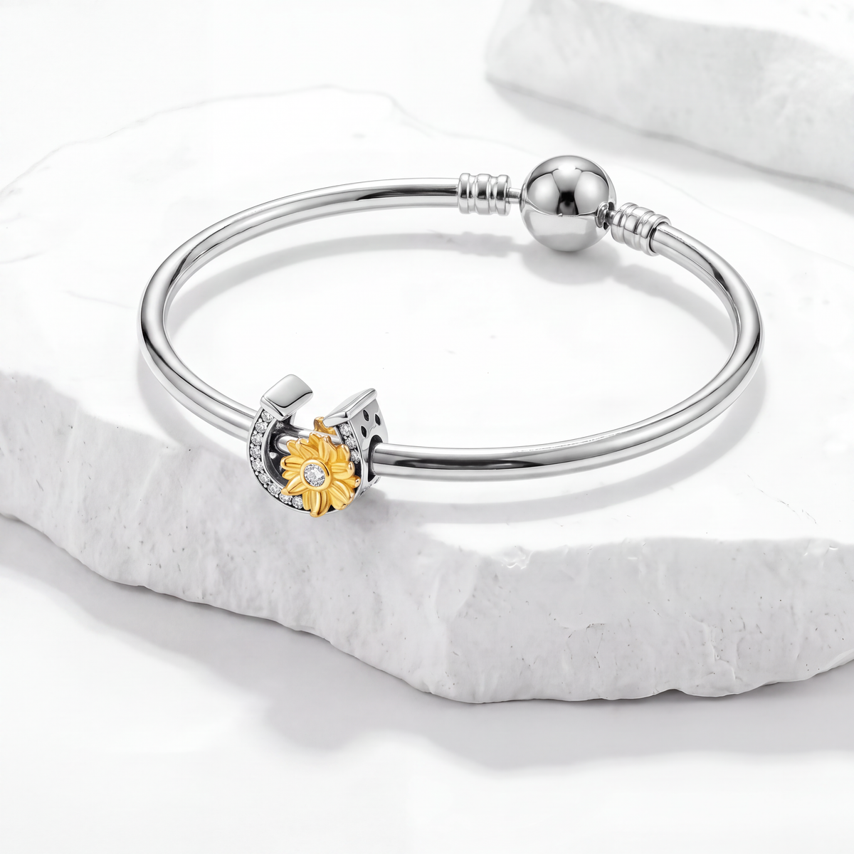 Charm collection featuring a silver bracelet with a floral charm and diamond accents in a stylish display.