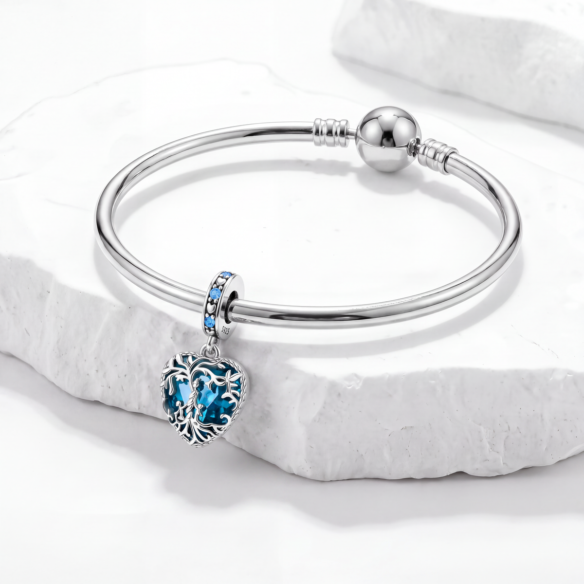 Elegant bracelet featuring a blue Nature Charms heart pendant on a marble background.