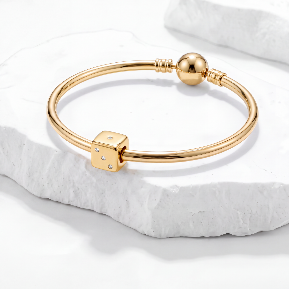 Hobby Charms gold bracelet with dice charm on white marble background.