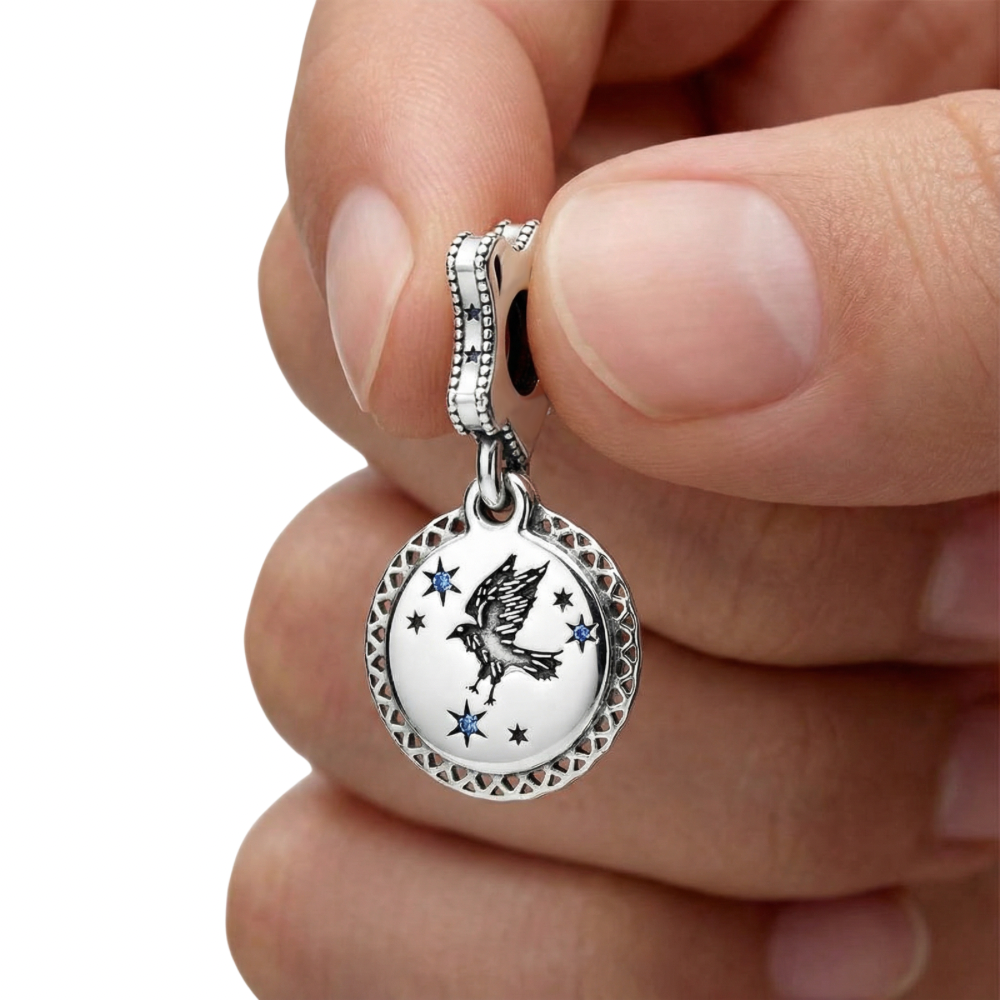 Close-up of a hand holding the Harry Potter Ravenclaw Dangle Charm with stars and a bird design.