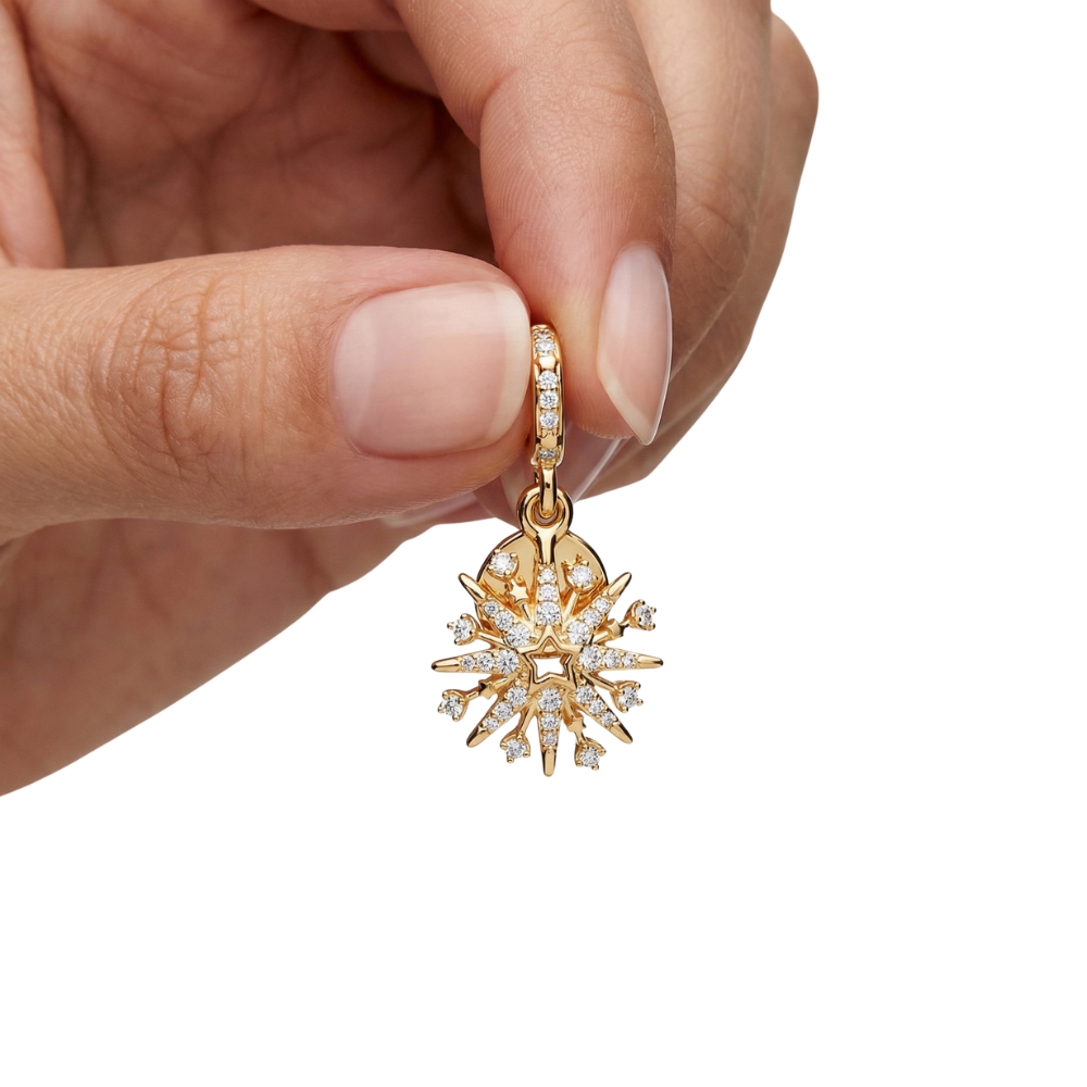 A hand holding the Golden Sparkling Starburst Pendant, showcasing its golden design and sparkling gems.
