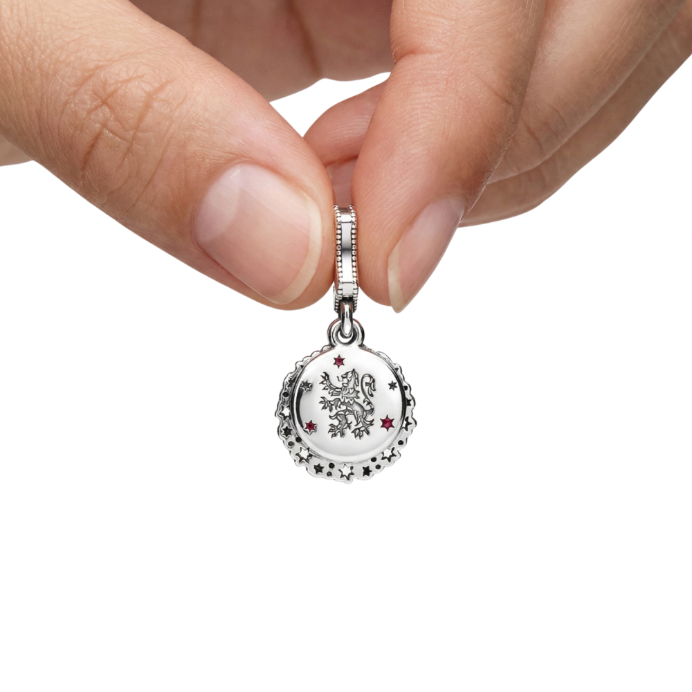 Hand holding a Harry Potter Gryffindor Dangle Charm featuring a lion design and stars.