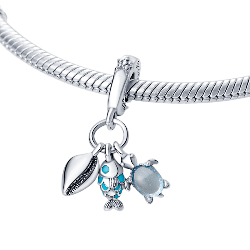 Explore the Ocean Triple Dangle Charm featuring a silver shell, teal fish, and glass dome sea turtle.